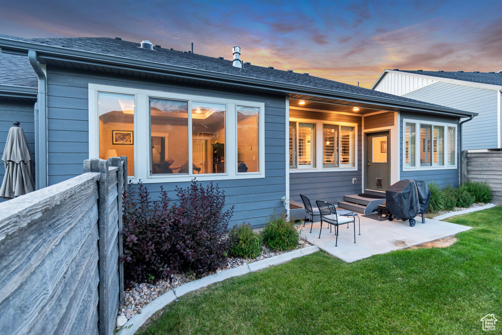 Back of property at dusk featuring a patio area