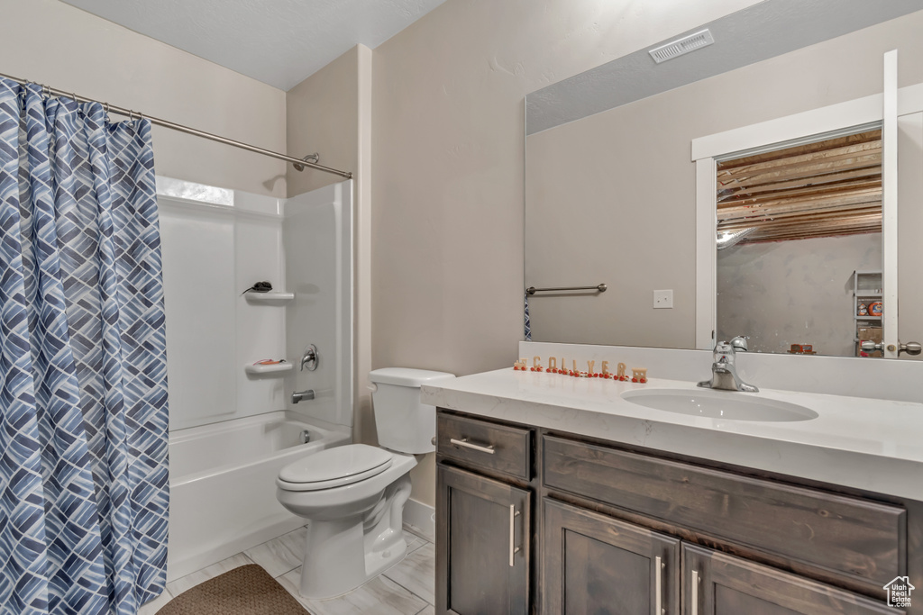 Full bath featuring vanity, shower / bath combo with shower curtain, toilet, and marble look tiles