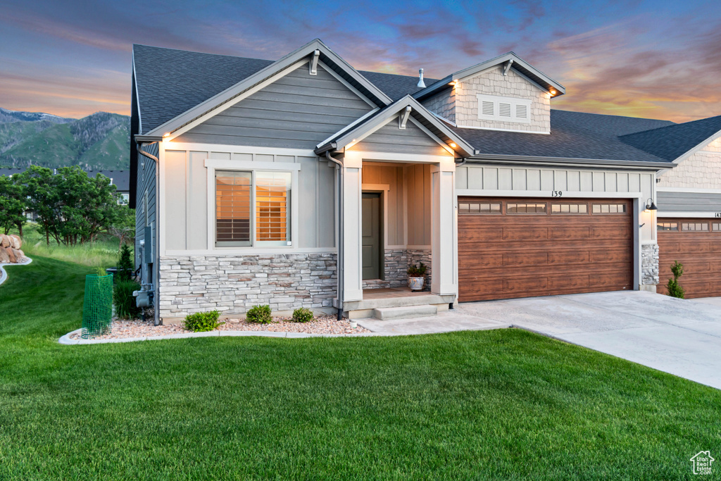 View of front of property featuring board and batten siding, an attached garage, a shingled roof, and driveway