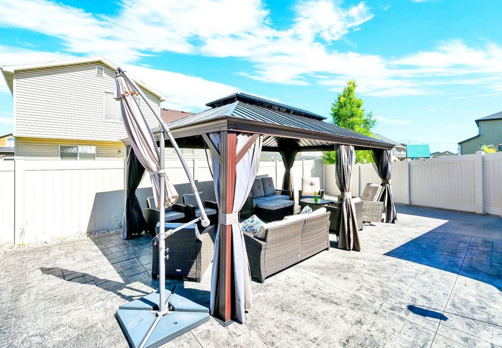 Fenced backyard featuring an outdoor living space, a gazebo, and a patio