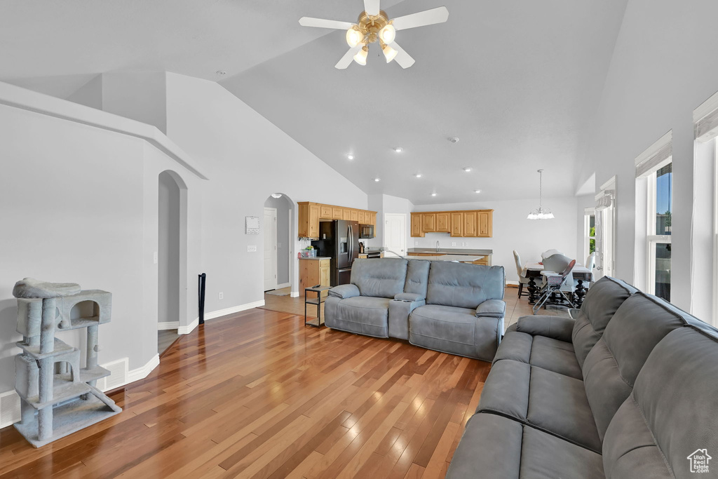 Living area featuring a ceiling fan, high vaulted ceiling, arched walkways, light wood-type flooring, and recessed lighting