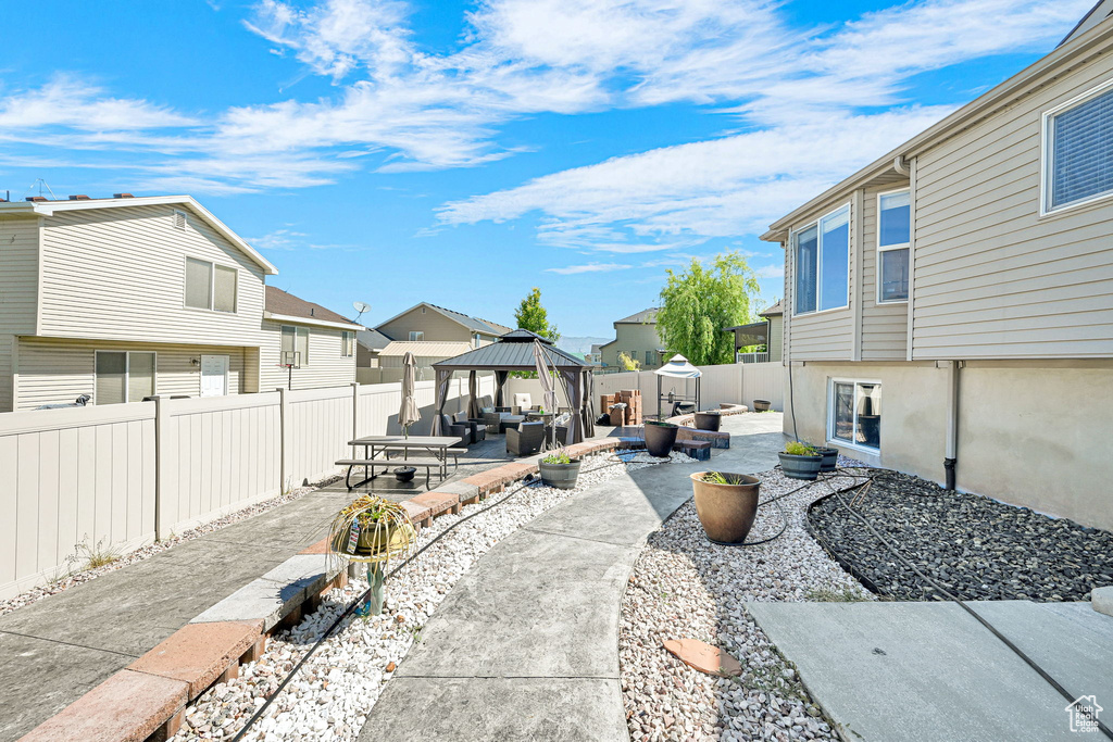 Fenced backyard with a gazebo, a residential view, an outdoor living space, and a patio area