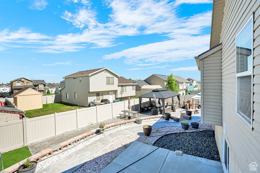 Fenced backyard featuring a gazebo, a residential view, and a patio area