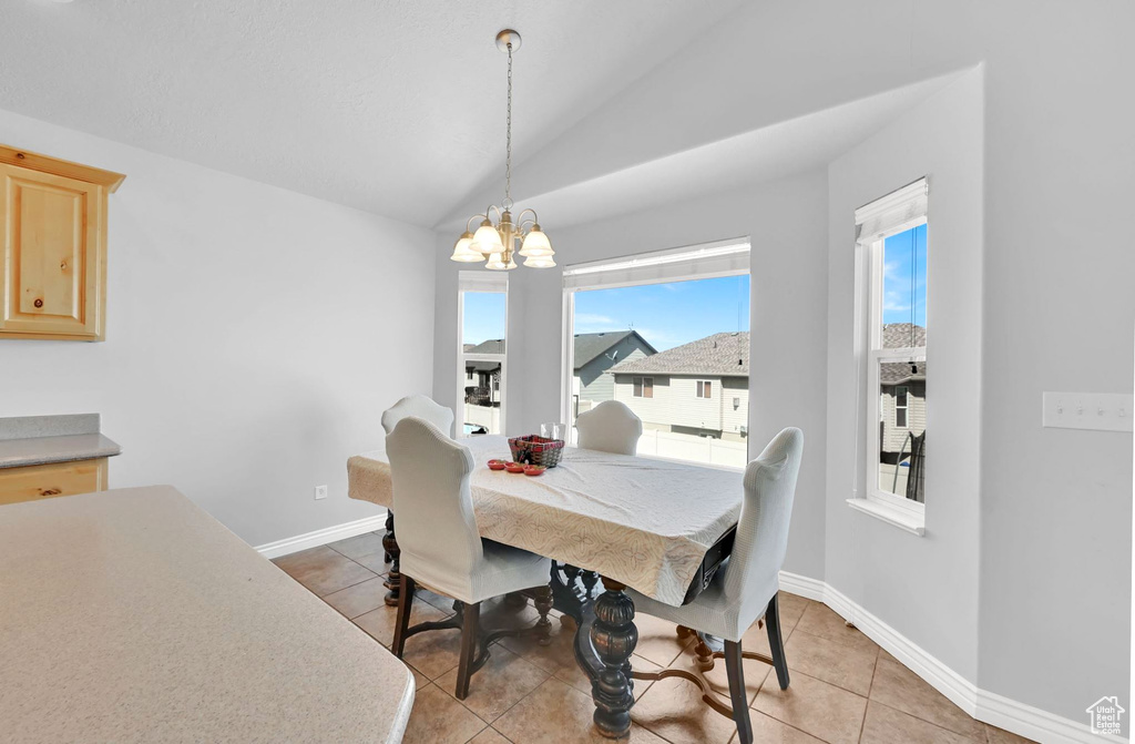 Dining area with a chandelier, light tile patterned floors, and lofted ceiling