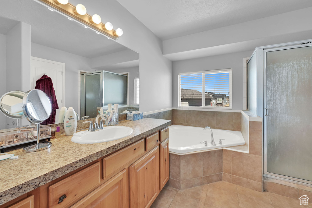 Bathroom featuring vanity, tile patterned flooring, a shower stall, and a garden tub