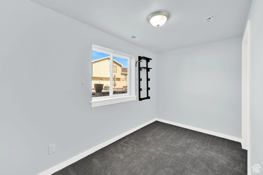 Unfurnished room with baseboards and dark carpet