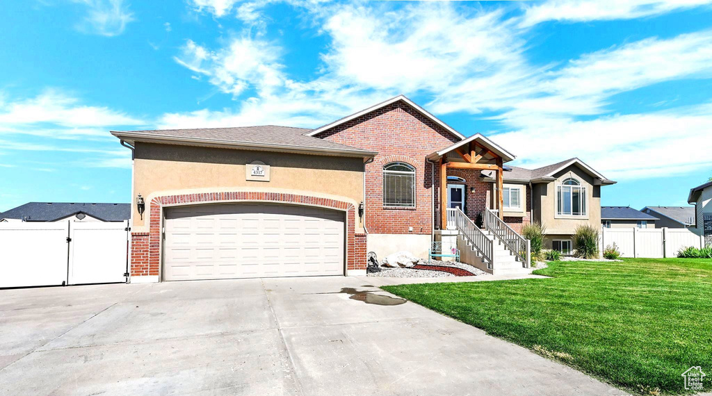 View of front of house featuring brick siding, concrete driveway, a garage, and a gate