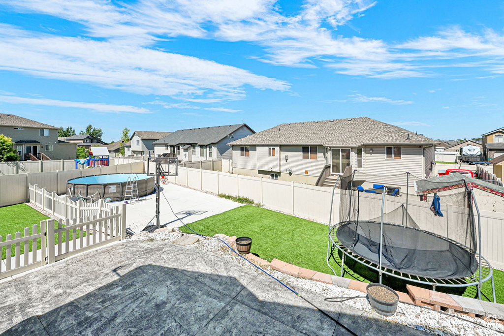 Fenced backyard with a trampoline, a residential view, and a patio