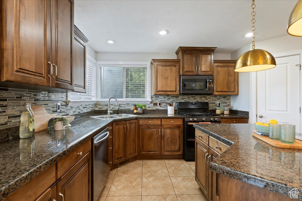 Kitchen with black stove, dishwasher, backsplash, light tile patterned floors, and decorative light fixtures