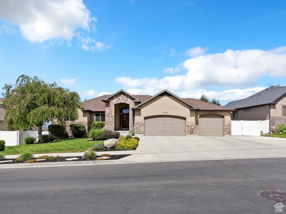 View of front of home featuring stone siding, stucco siding, an attached garage, and concrete driveway