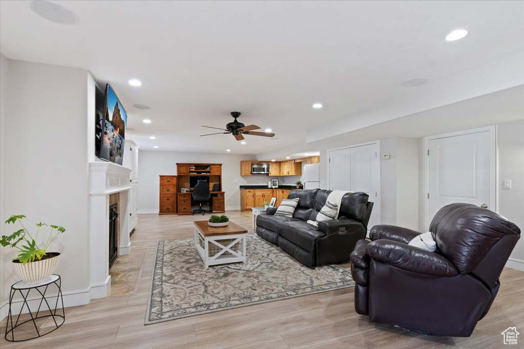 Living area with recessed lighting, an office area, light wood finished floors, and a fireplace with flush hearth