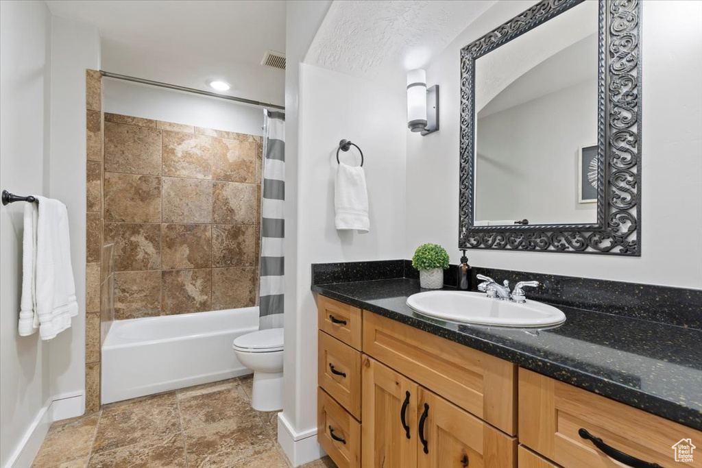 Bathroom with vanity, shower / tub combo, and stone finish flooring