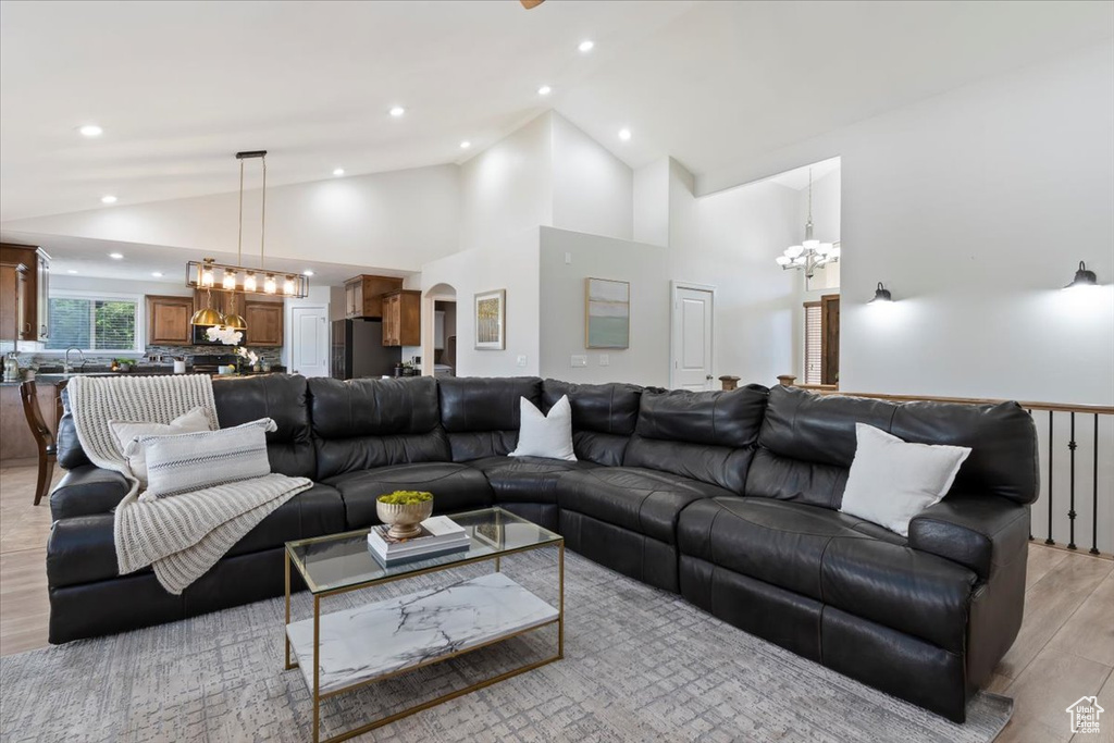 Living area featuring a chandelier, arched walkways, light wood-type flooring, recessed lighting, and high vaulted ceiling