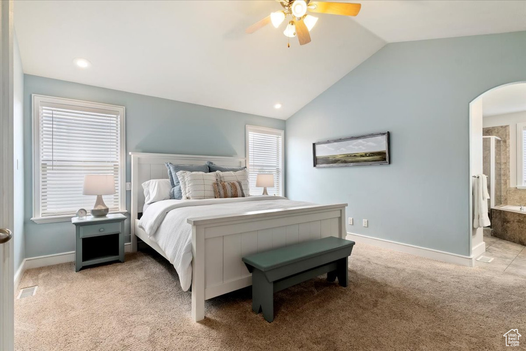 Bedroom with lofted ceiling, arched walkways, light carpet, ceiling fan, and ensuite bathroom