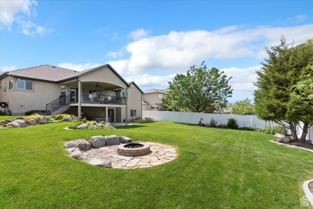 View of yard featuring an outdoor fire pit, stairs, ceiling fan, and a patio