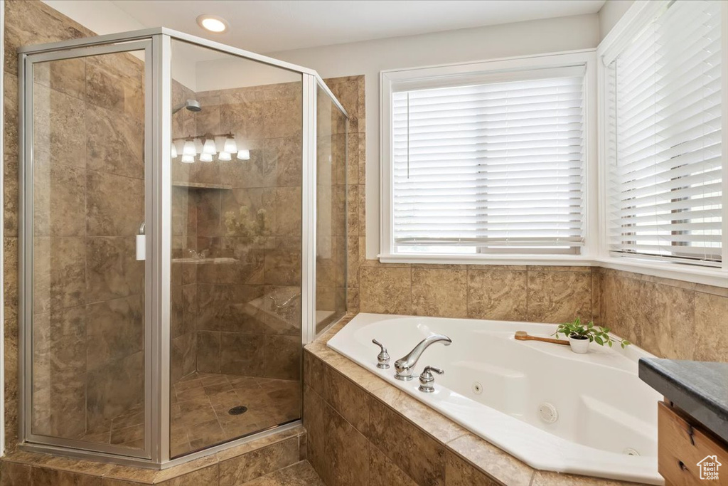 Bathroom featuring a jetted tub, healthy amount of natural light, a stall shower, and vanity