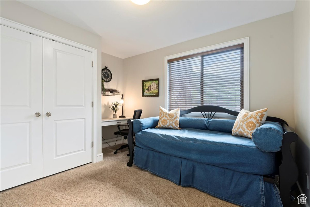 Bedroom featuring light carpet, a closet, and an office area