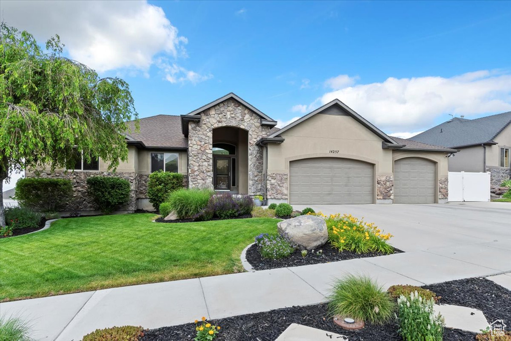 View of front facade featuring stucco siding, stone siding, an attached garage, and concrete driveway