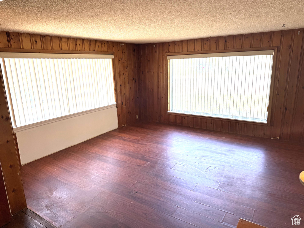 Spare room featuring wood finished floors, a textured ceiling, and wooden walls