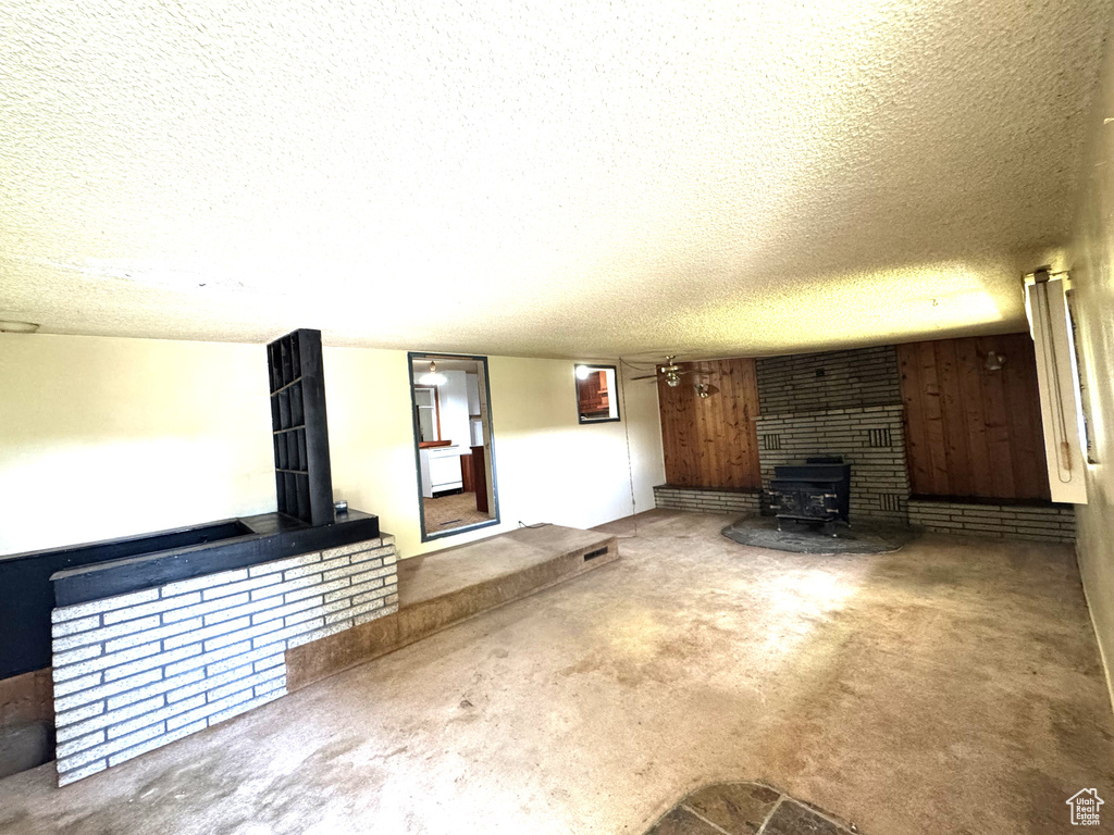 Unfurnished living room with a wood stove, a textured ceiling, and carpet