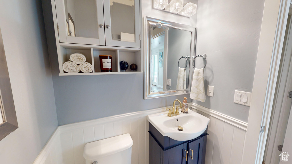 Half bath with a wainscoted wall, vanity, and a decorative wall