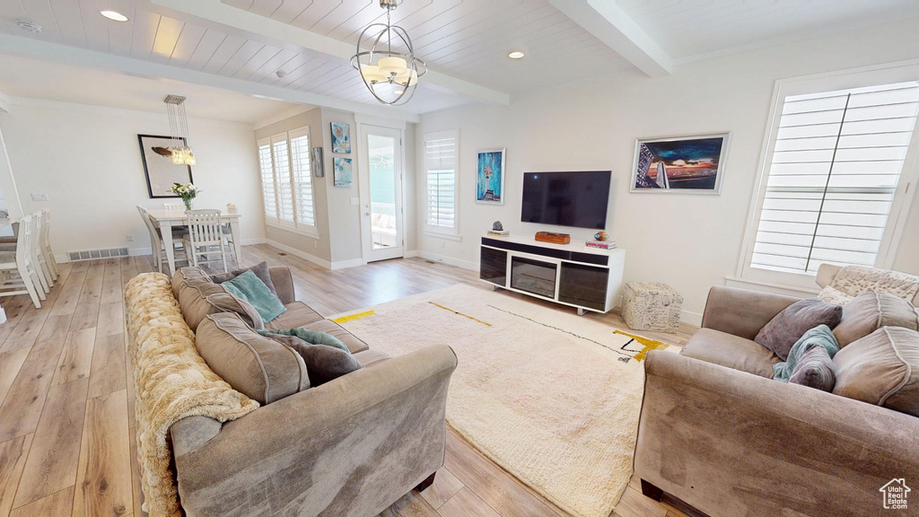 Living room with a chandelier, light wood finished floors, beam ceiling, and recessed lighting