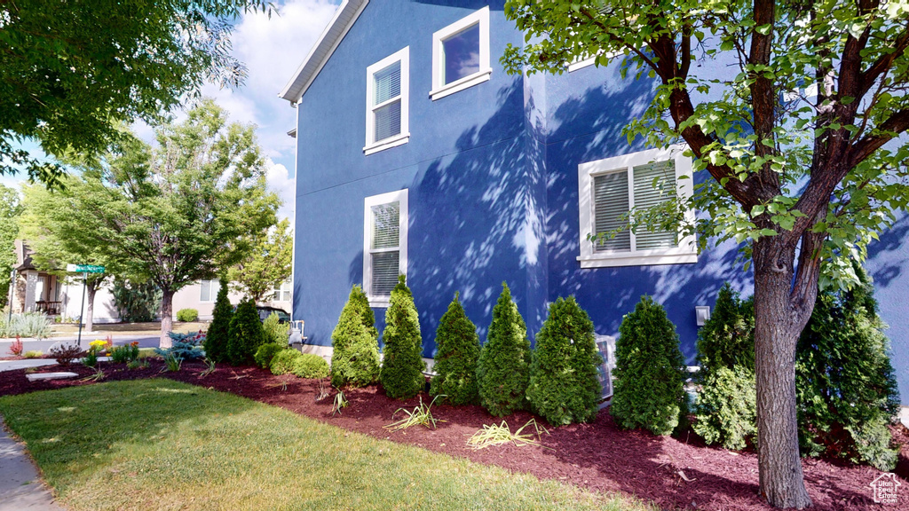 View of property exterior with stucco siding and a lawn