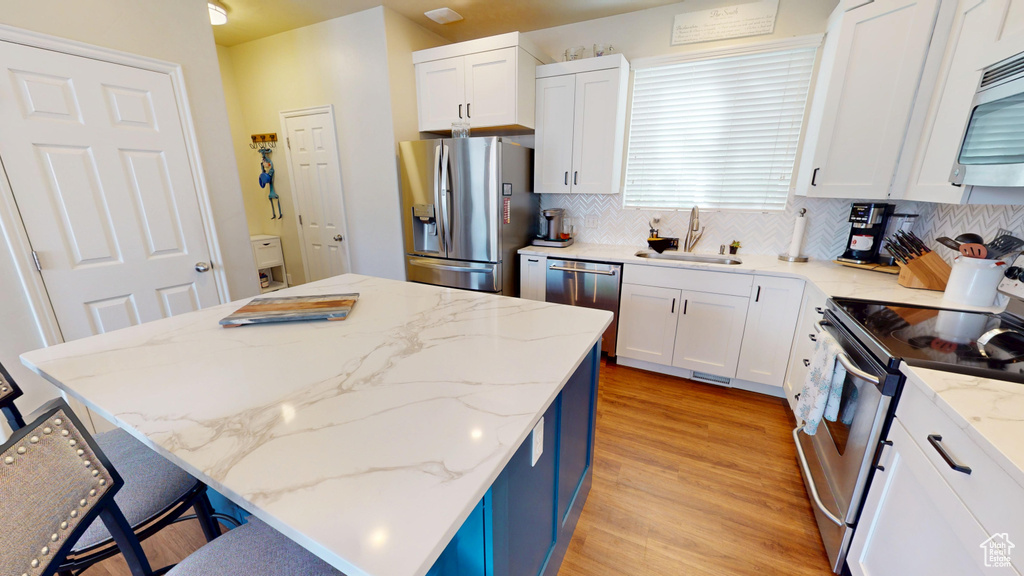 Kitchen with appliances with stainless steel finishes, a kitchen island, backsplash, and a kitchen breakfast bar