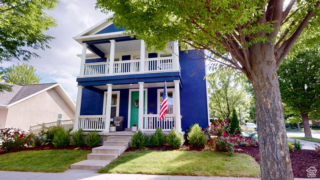 View of front of house featuring a balcony, a porch, a front lawn, and stucco siding
