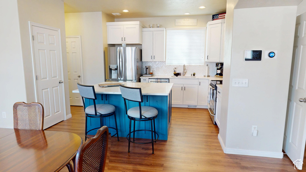 Kitchen featuring appliances with stainless steel finishes, light wood-style floors, a center island, and recessed lighting
