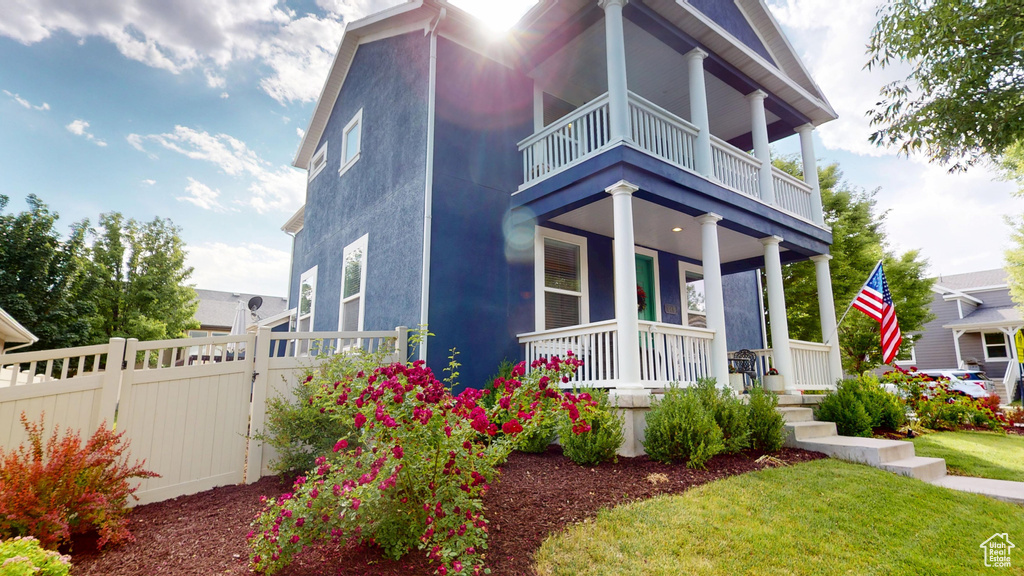 View of front facade with a balcony, a porch, and stucco siding