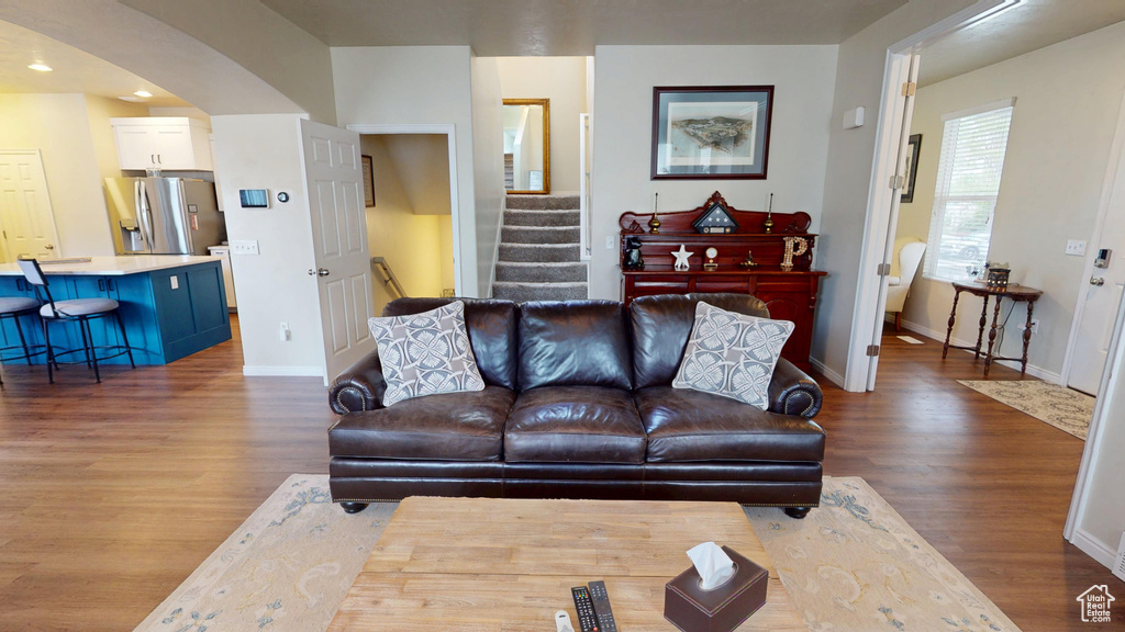 Living room with arched walkways, wood finished floors, stairway, and recessed lighting