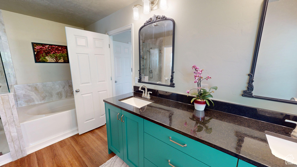 Bathroom featuring double vanity, a bath, and wood finished floors