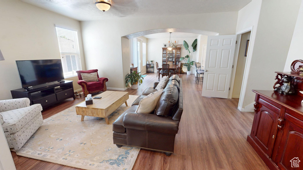 Living area with arched walkways, wood finished floors, and a chandelier
