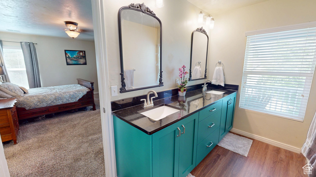 Bathroom featuring double vanity, plenty of natural light, connected bathroom, and wood finished floors