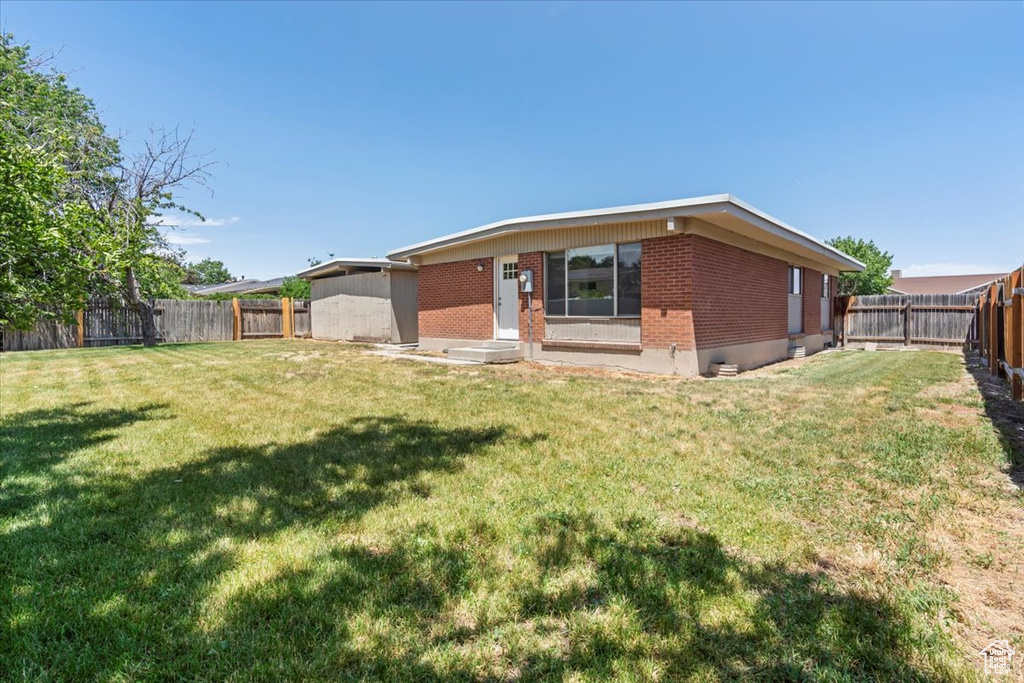 Back of property with brick siding and a fenced backyard