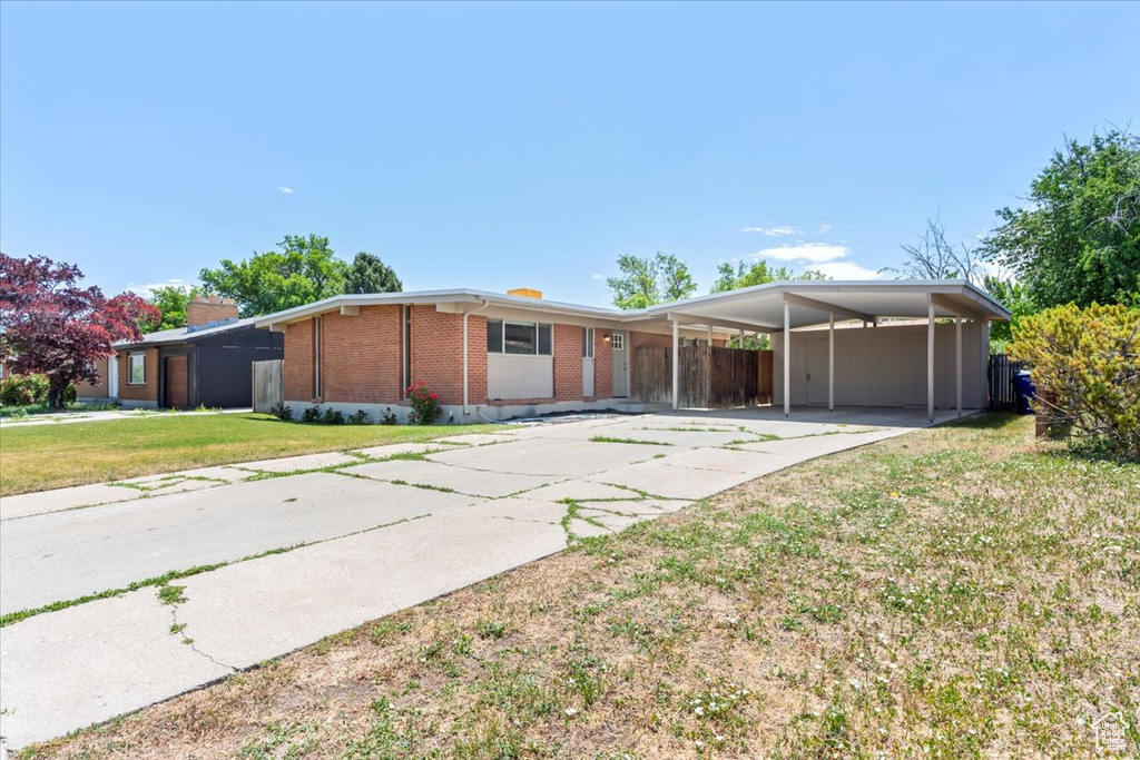 View of front facade featuring brick siding, driveway, an attached carport, and a chimney