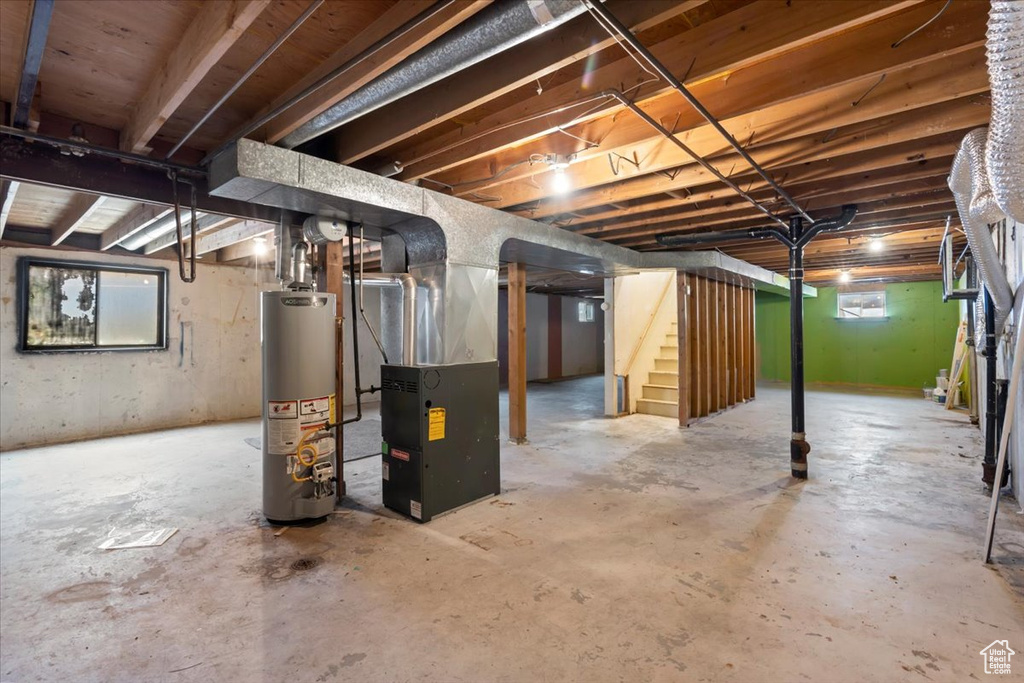 Below grade area featuring gas water heater, stairway, and heating unit