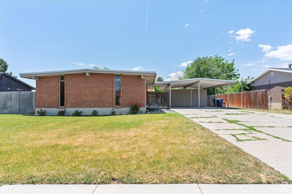 View of front facade with brick siding, concrete driveway, and an attached carport