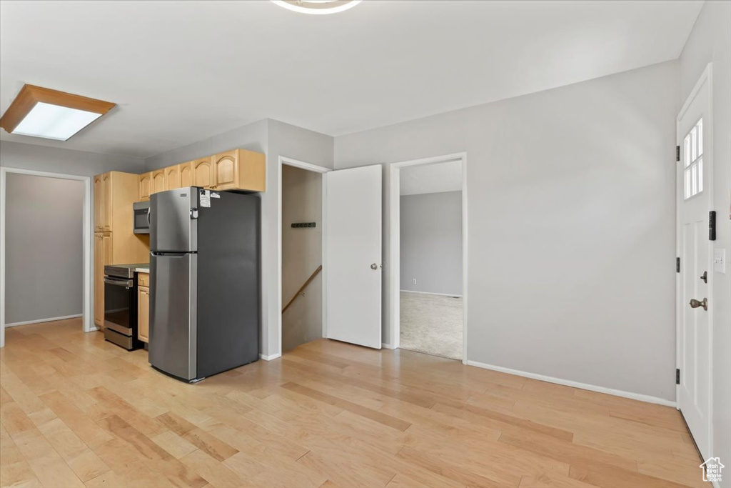 Kitchen featuring appliances with stainless steel finishes, light brown cabinetry, and light wood finished floors