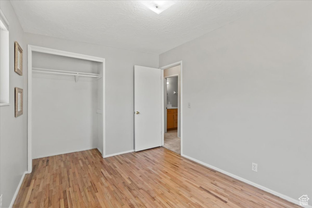 Unfurnished bedroom featuring light wood finished floors, a closet, and a textured ceiling
