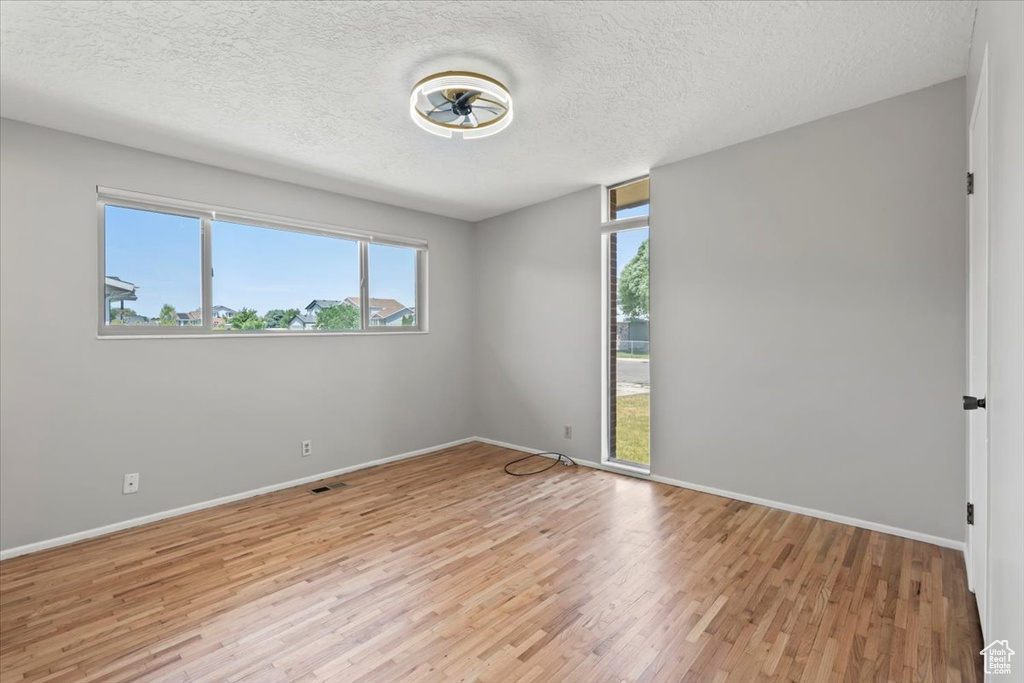Unfurnished room with light wood-style flooring and a textured ceiling