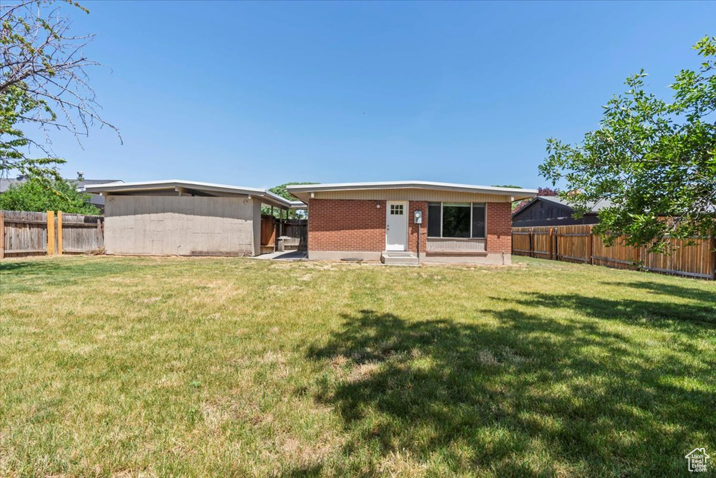 Back of property with entry steps, a fenced backyard, and brick siding