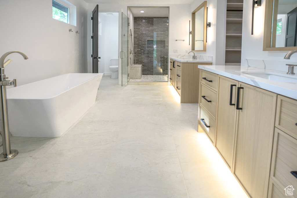 Full bathroom with a shower stall, two vanities, and a soaking tub