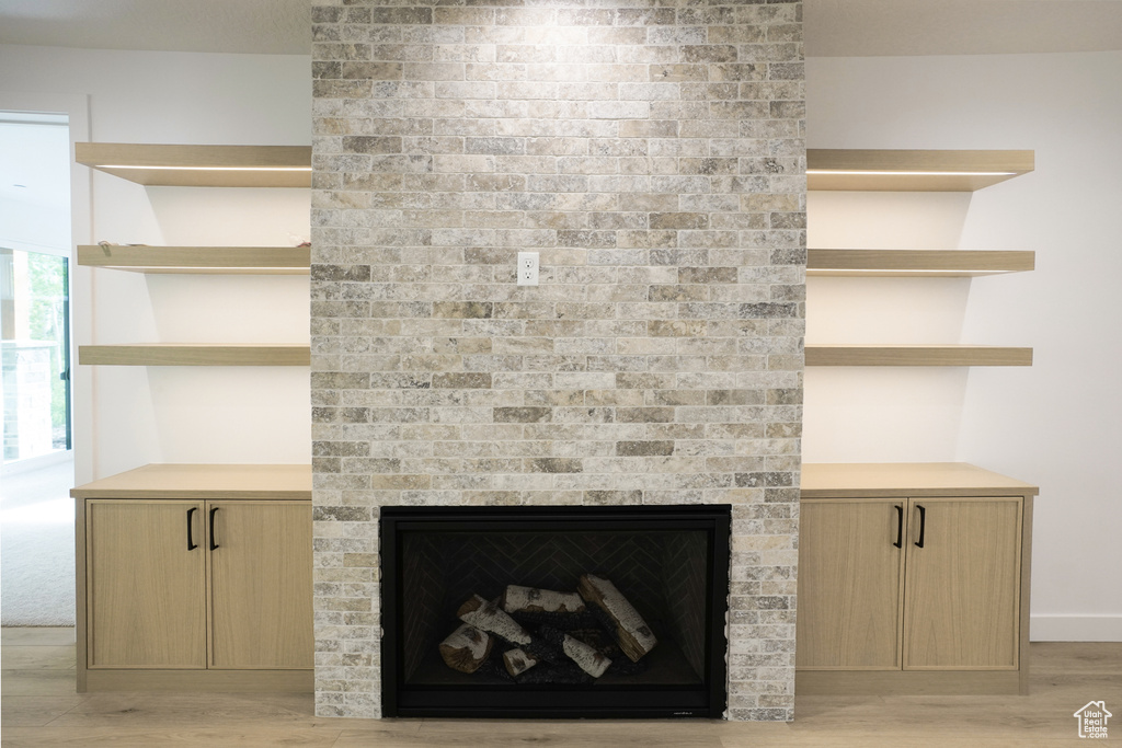 Detailed view of wood finished floors and a brick fireplace