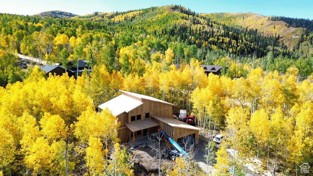 Aerial view of property and surrounding area with a forest and a mountain backdrop