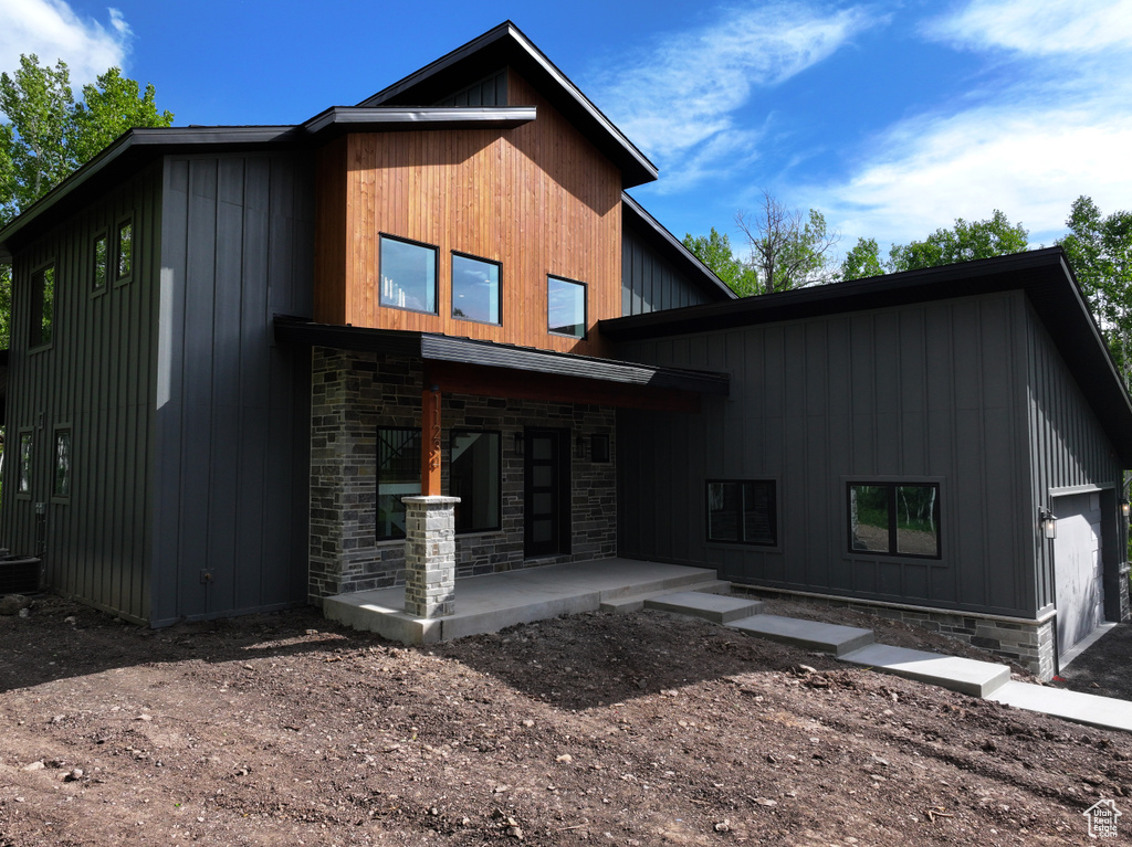 Rear view of property featuring stone siding and board and batten siding