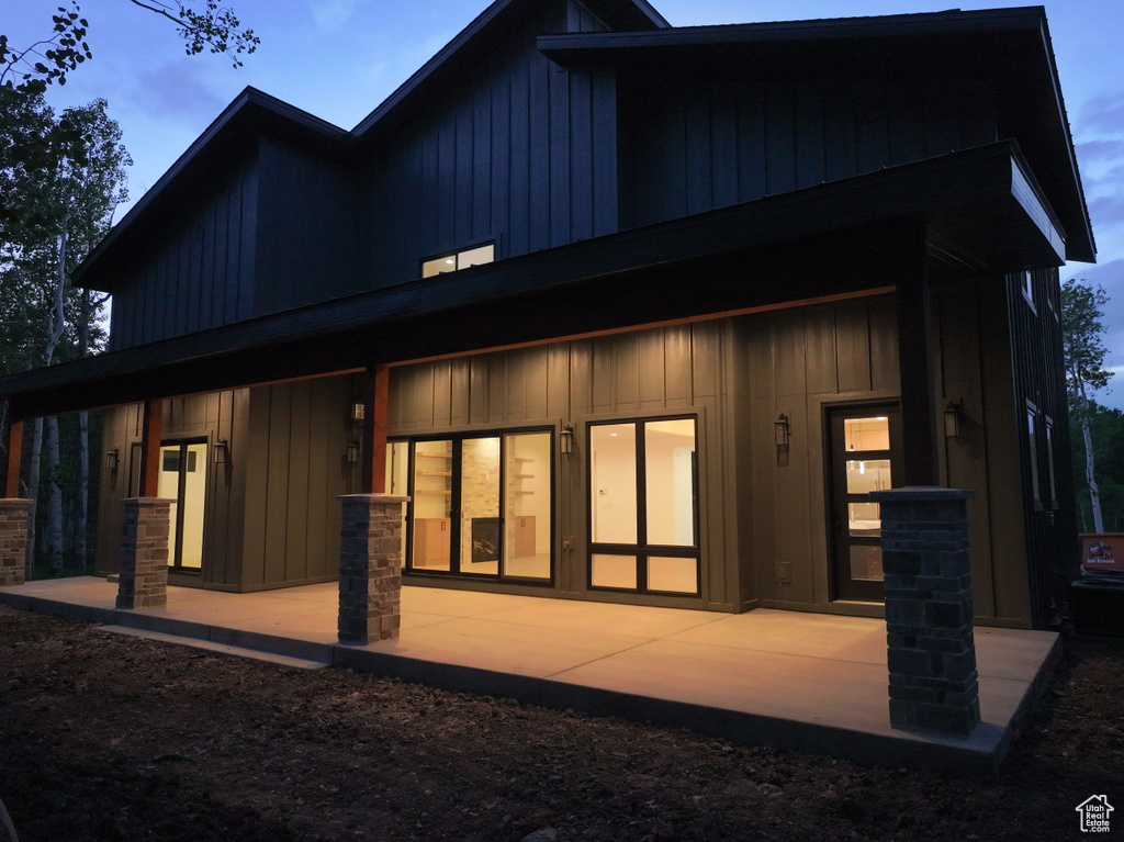 Rear view of property with board and batten siding and a patio