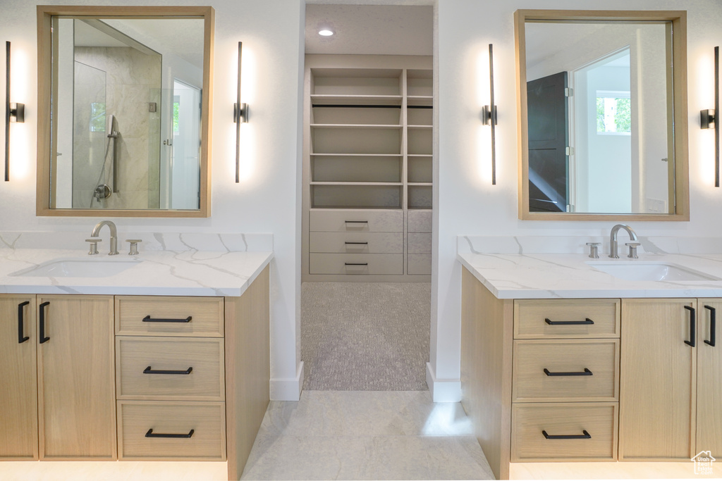 Bathroom featuring two vanities, a walk in shower, tile patterned floors, and a spacious closet