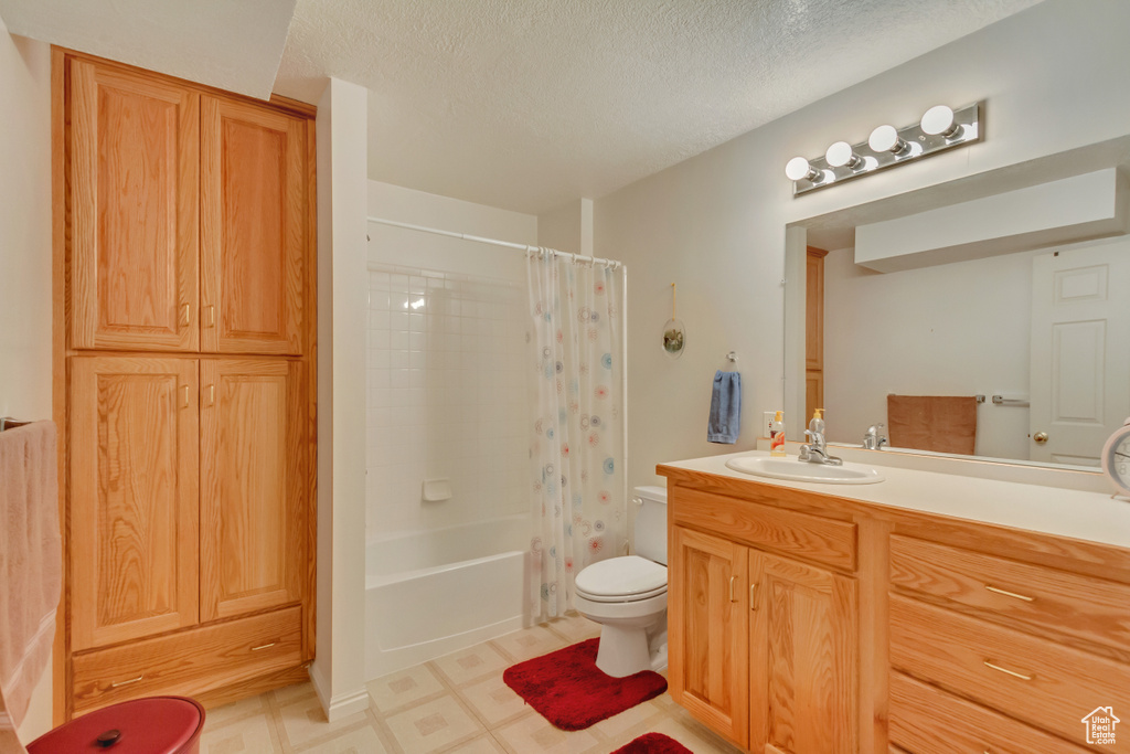 Full bath featuring vanity, shower / bathtub combination with curtain, tile patterned floors, and a textured ceiling